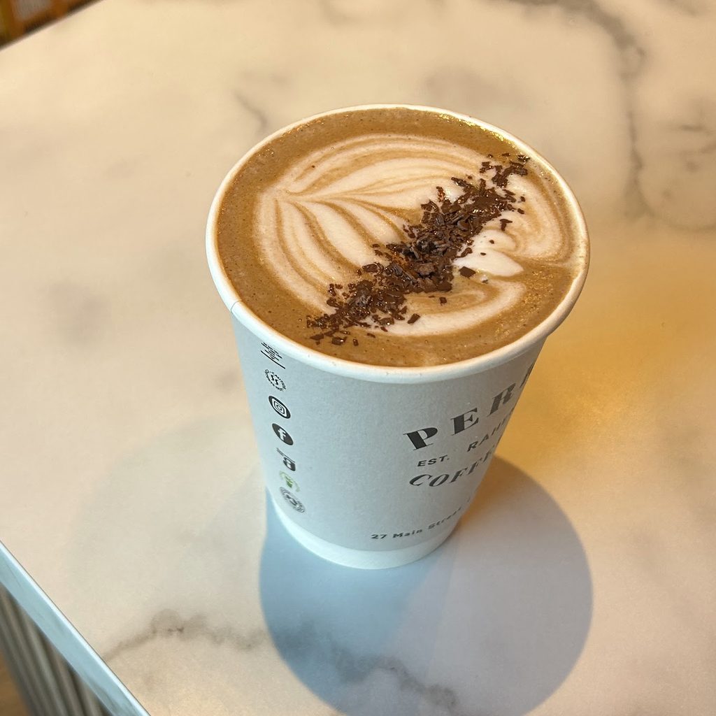 A takeaway coffee with latte art and chocolate shavings on the marble counter