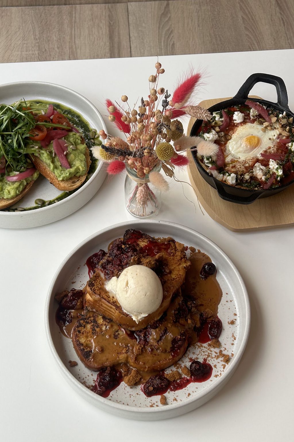 Avocado toast, a baked egg skillet and French toast with berry compote laid out on a table